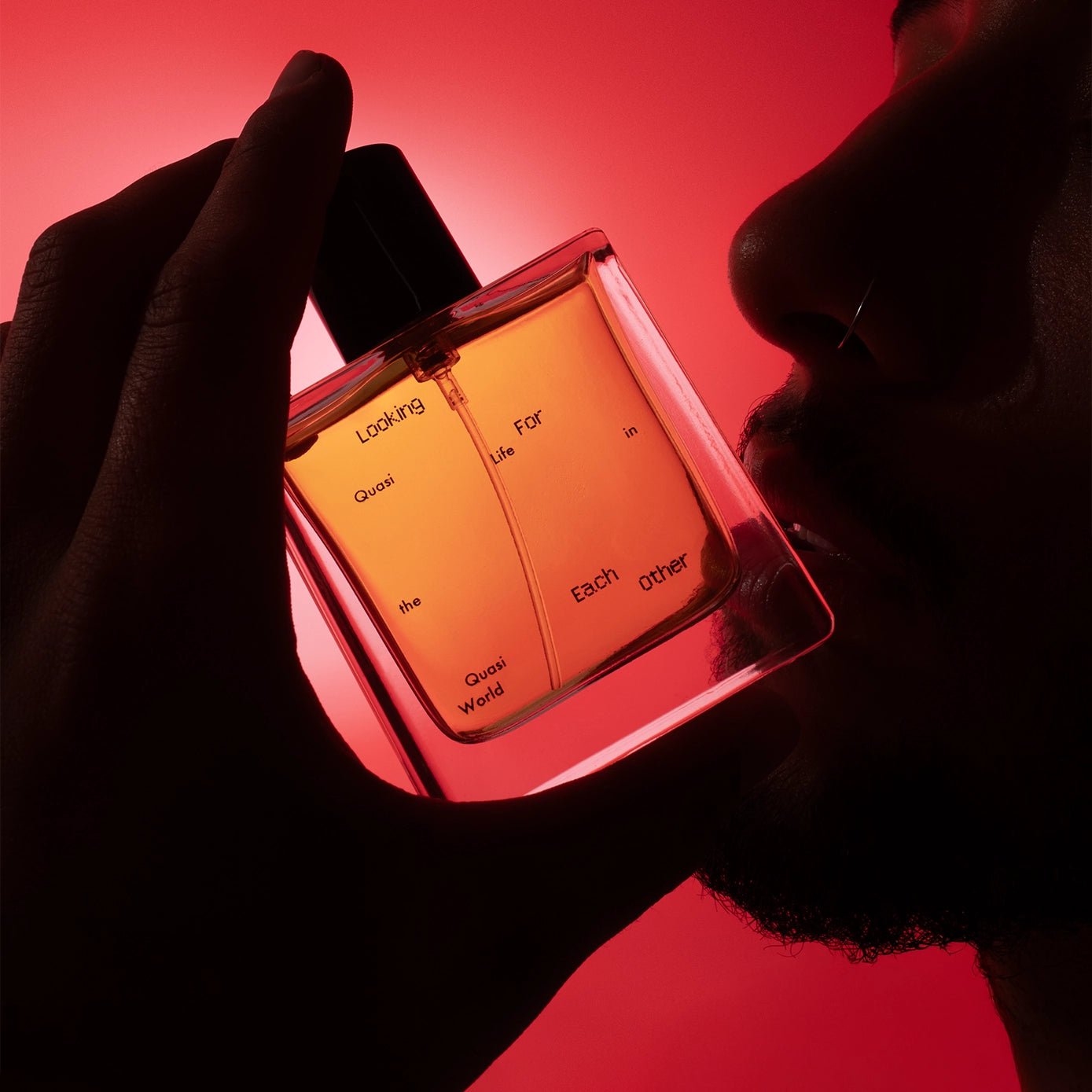 Hand holding a 50ml bottle of Blinding Reflection from Tower Window by Looking for Each Other, set against a vivid red background. The bottle’s minimal label and radiant lighting echo the fragrance’s bright, spiced citrus character.