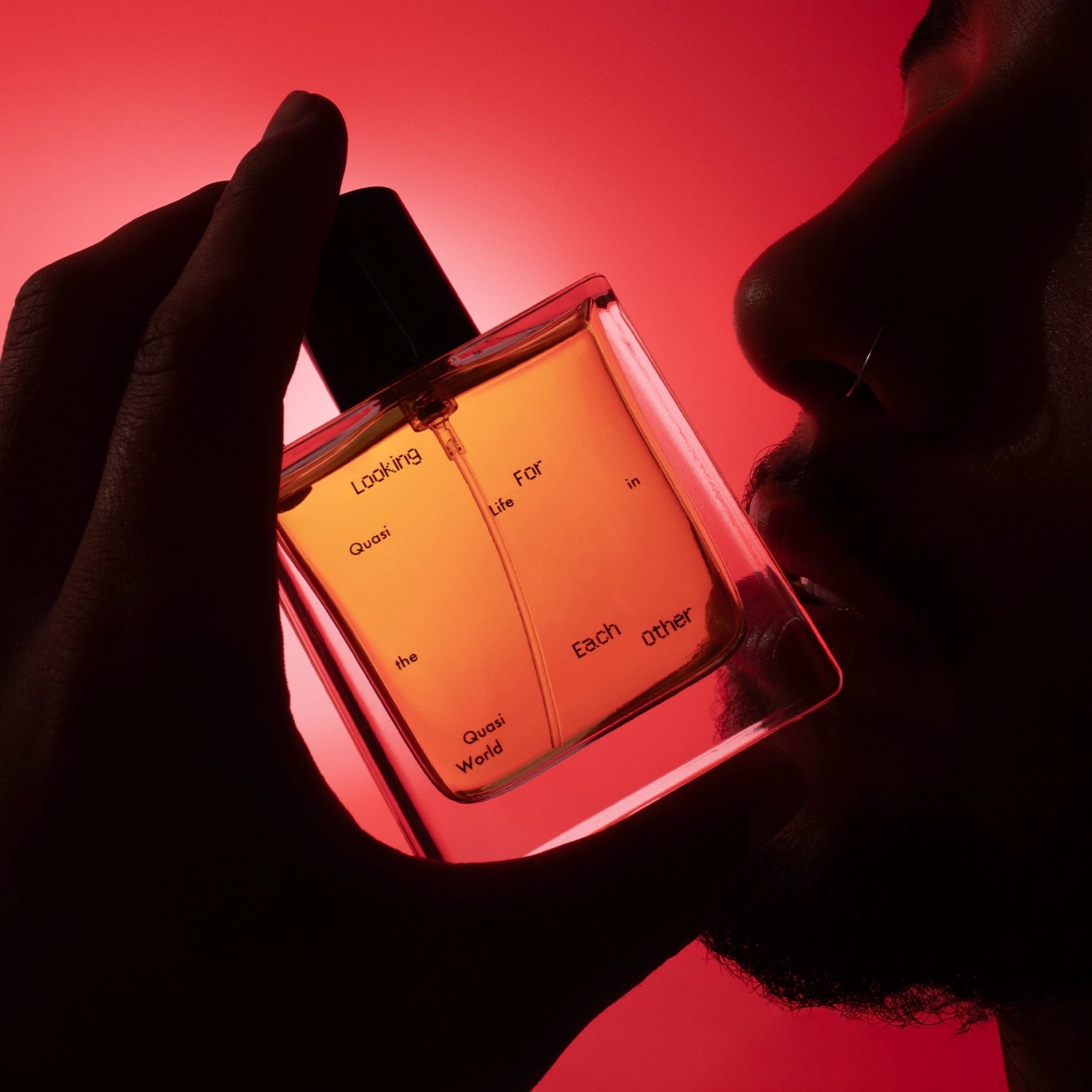 Silhouette of a person holding Quasi Life in the Quasi World by Looking for Each Other up to their face; dramatic red light creates a sensual, surreal atmosphere emphasizing the bottle’s glow.