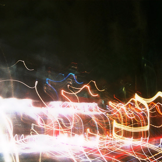 Long-exposure photo of multicolored light trails bursting across a black backdrop—radiant, electric, and sun-charged. Symbolizes the energized brightness of the Radiant scent feel from Looking for Each Other.