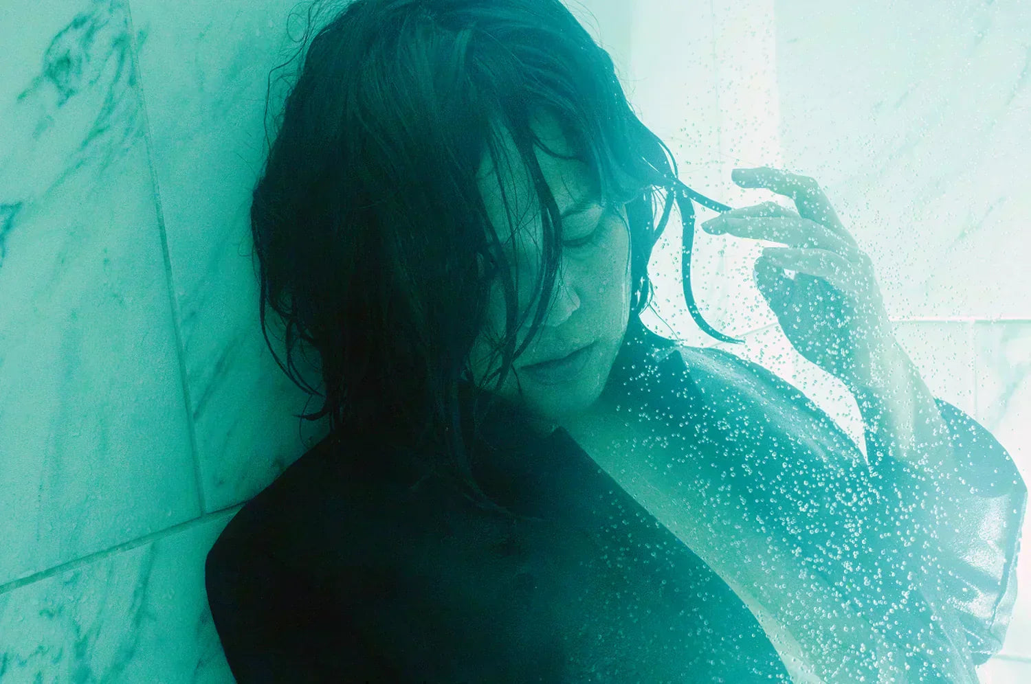 Editorial portrait of Mariele Atienza with wet hair and dark blazer in marble-tiled shower for LFEO.